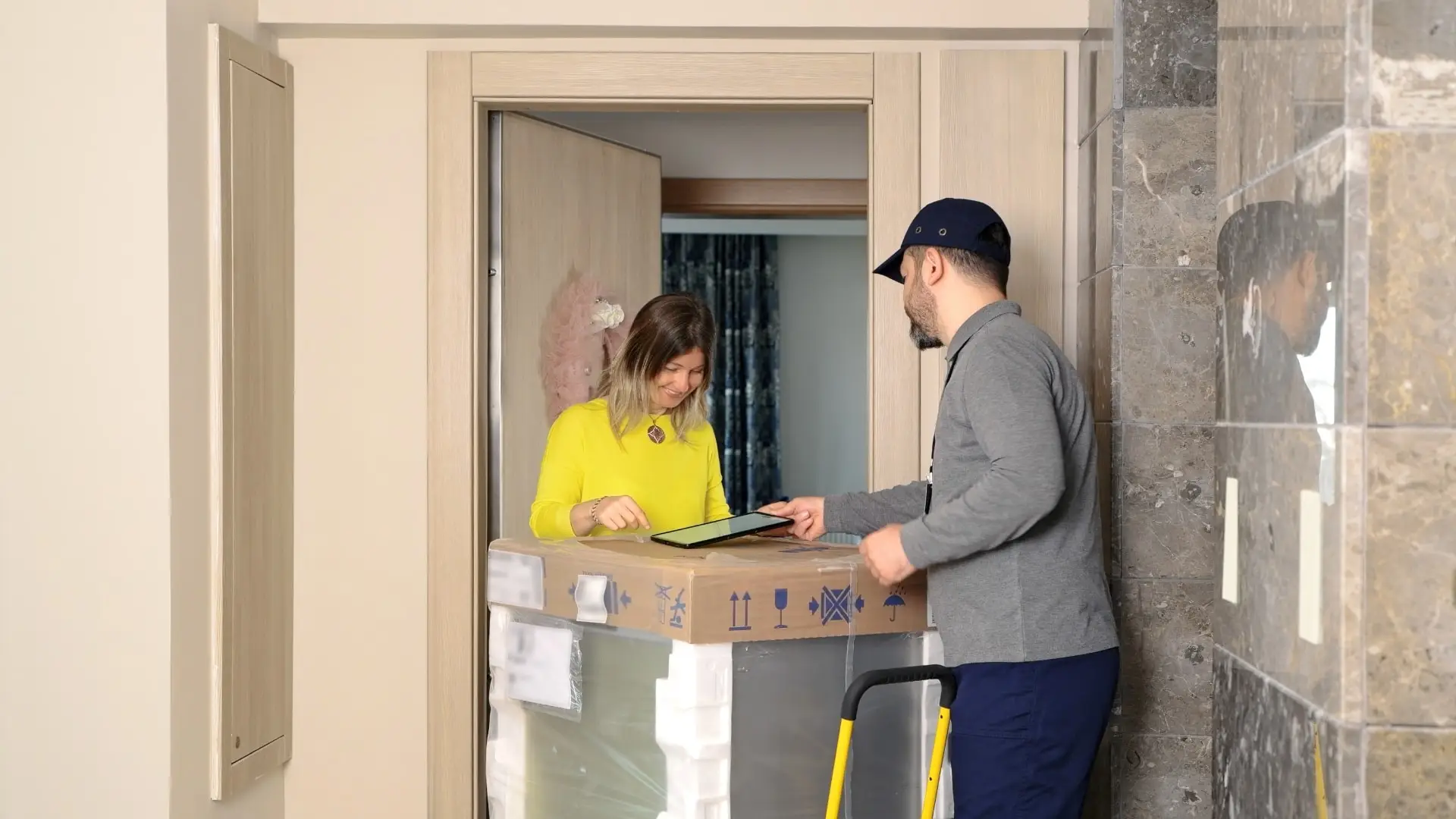 A logistics professional delivery an appliance to a customer and her home.