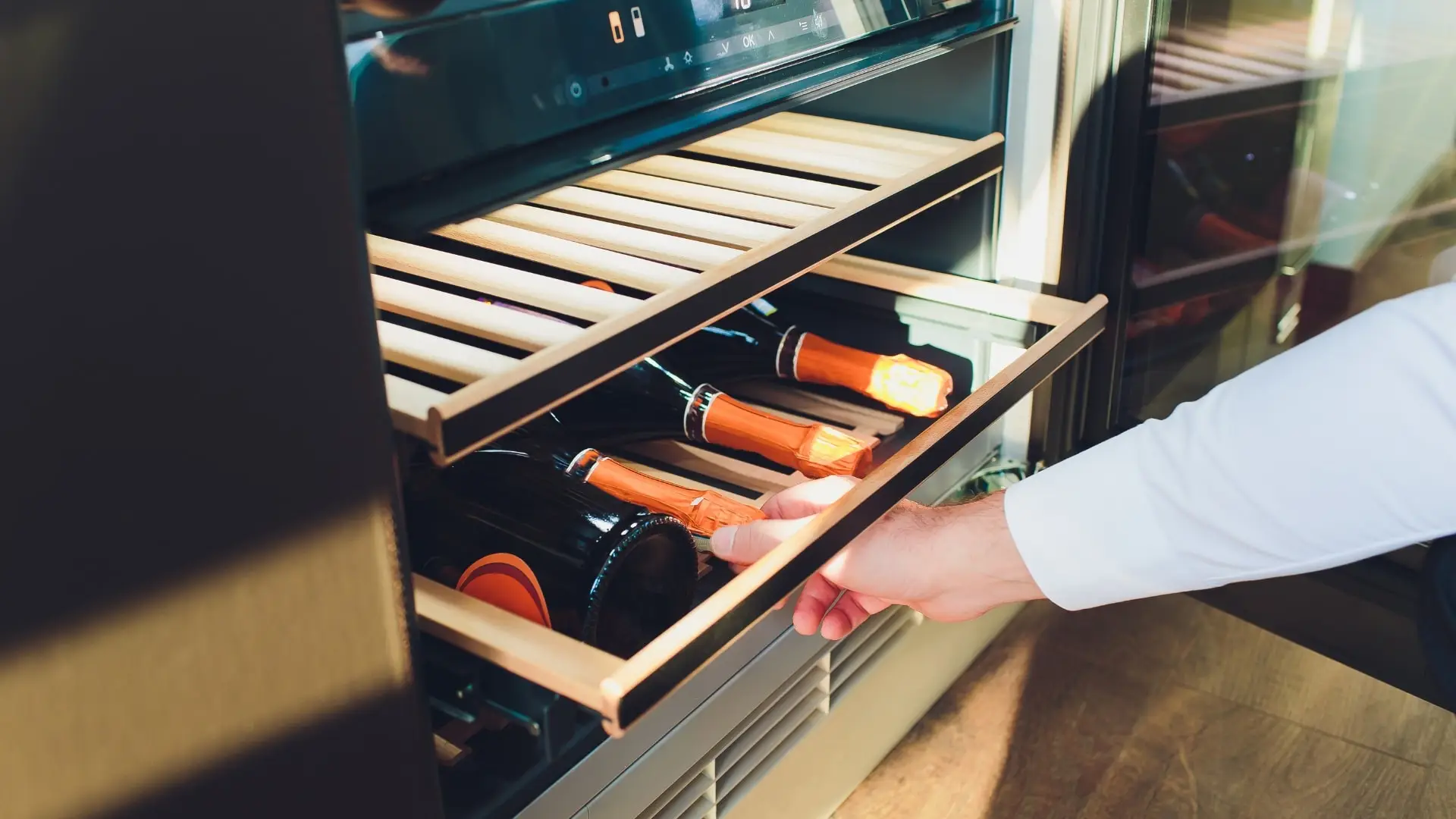 Man opening a wine cellar to grab a wine bottle.