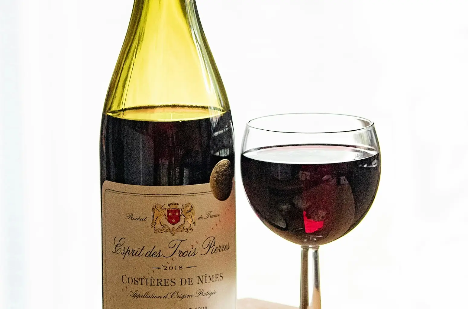 Nice red wine bottle along a glass mostly full.